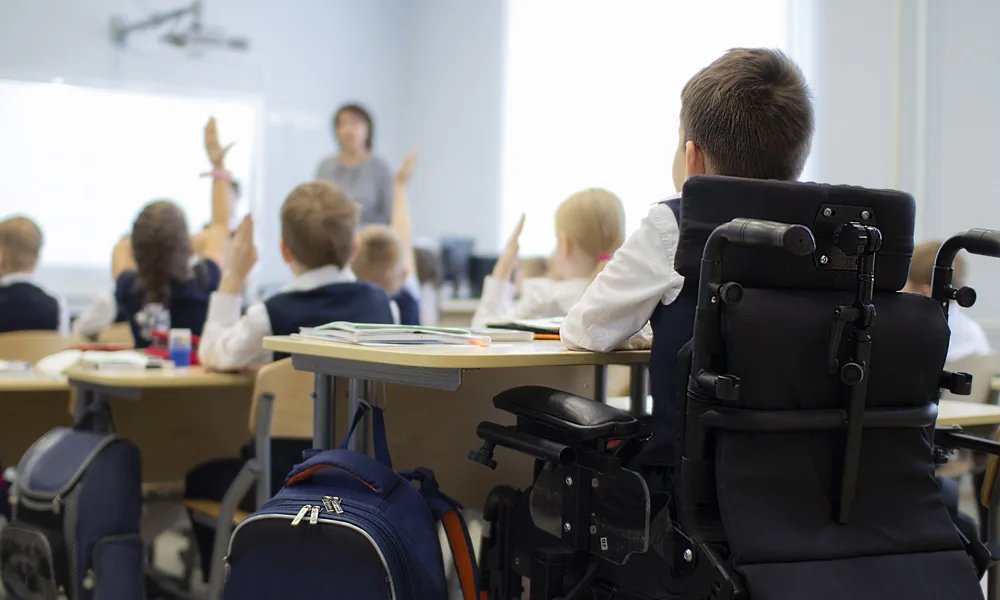 Élève en fauteuil roulant levant la main dans une salle de classe