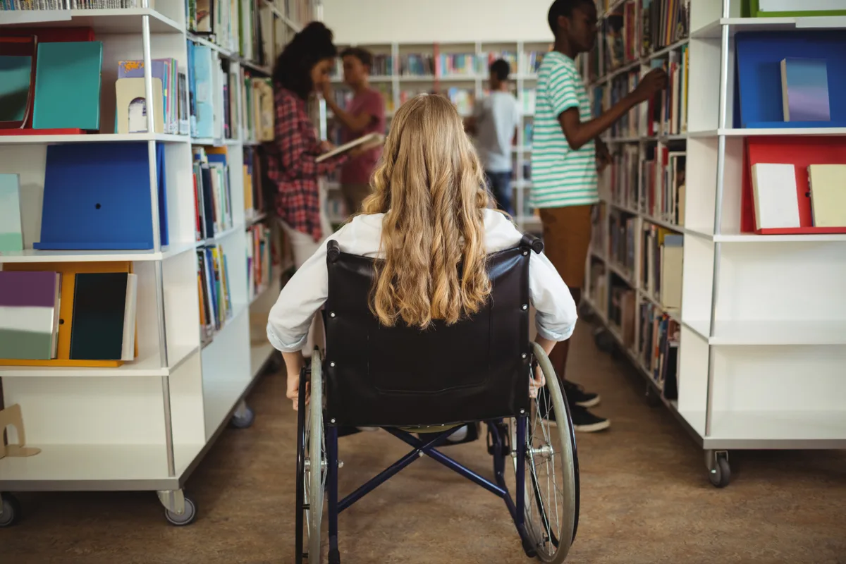 Jeune fille en fauteuil roulant dans une bibliothèque