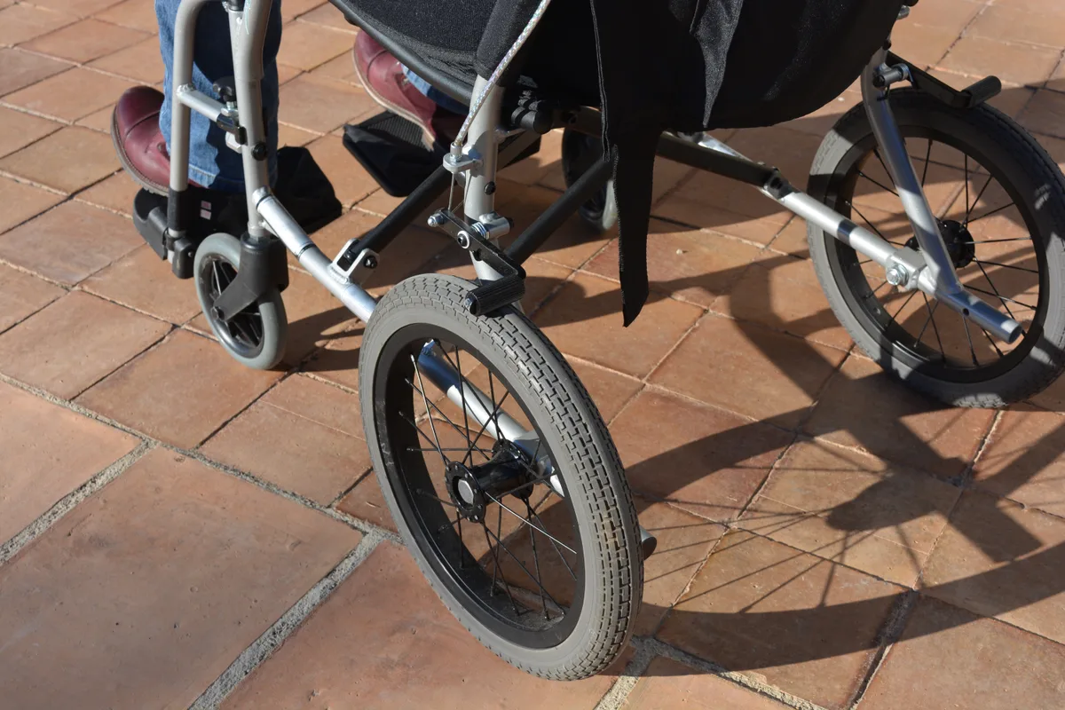 Roues d’un fauteuil roulant sur un sentier extérieur