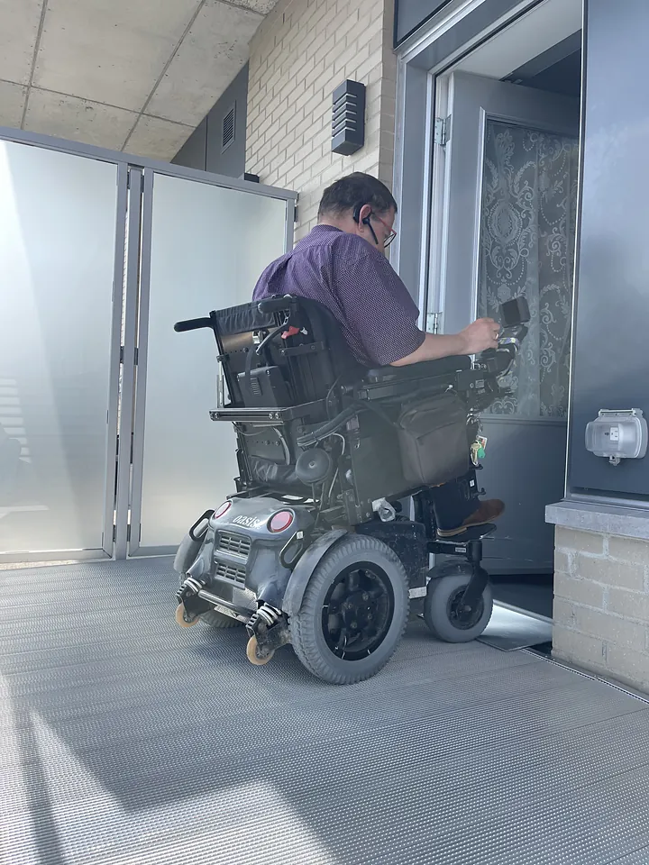 Personne en fauteuil roulant motorisé passant la porte vers la plateforme de balcon